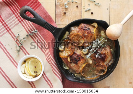 Chicken thighs with lemon slices, oregano, garlic and white wine in a pan