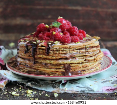 Pancake cake with fresh raspberry, pistachios and dark chocolate sauce perfect for  pancake week and Easter