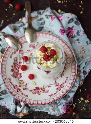 White chocolate whipped cream dessert with fresh raspberry and chopped pistachios in a jar, selective focus