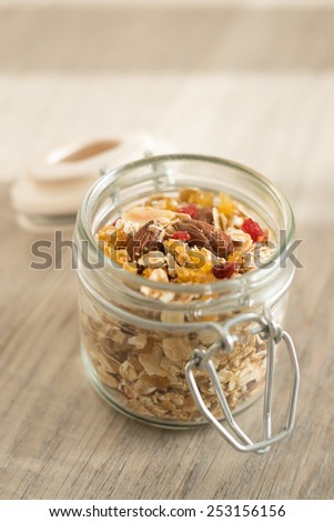 Homemade granola with oat flakes, honey, brown sugar, nuts and dried fruits in a jar, selective focus