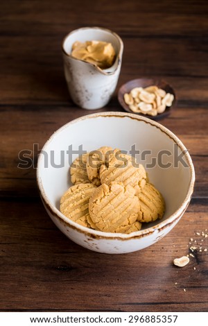 Freshly baked homemade peanut butter cookies with peanuts in a bowl and a cup of peanuts butter, selective focus