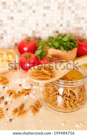 Italian pasta in wooden spoon and glass jar with pasta