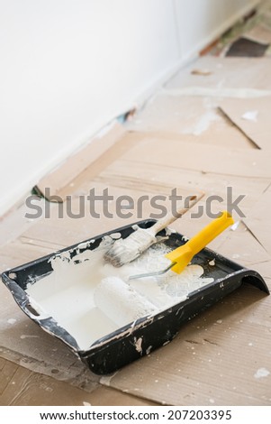 paint brush and paint roller with white paint