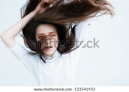 Beautiful fashion woman with orange nails, creative hairstyle and makeup - Model posing in studio