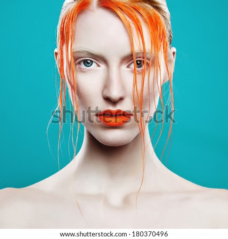Portrait of beautiful girl with orange hair on a blue background, closeup