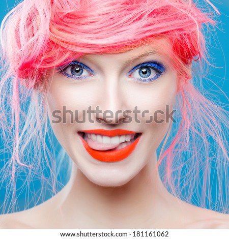 Portrait of beautiful girl with pink hair on a blue background, showing tongue