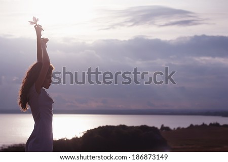 Free woman enjoying freedom feeling happy at beach at sunset. Beautiful serene relaxing woman in pure happiness and elated enjoyment with arms raised outstretched up.