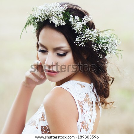 Portrait of a beautiful girl in a field with a wreath of flowers