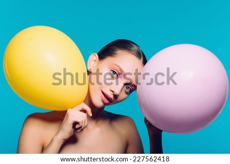 Portrait of a beautiful girl in the studio on a blue background with balloons, happy mood