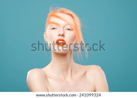 Portrait of beautiful young girl with orange hair on a blue background