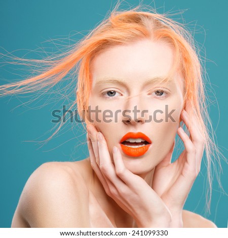 Portrait of beautiful girl with orange hair on a blue background, surprise