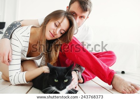 Beautiful man and woman in a white interior with a black cat