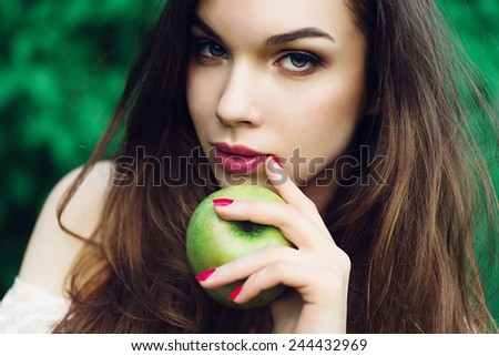 Portrait of beautiful brunette girl with green apple, concept of health and beauty