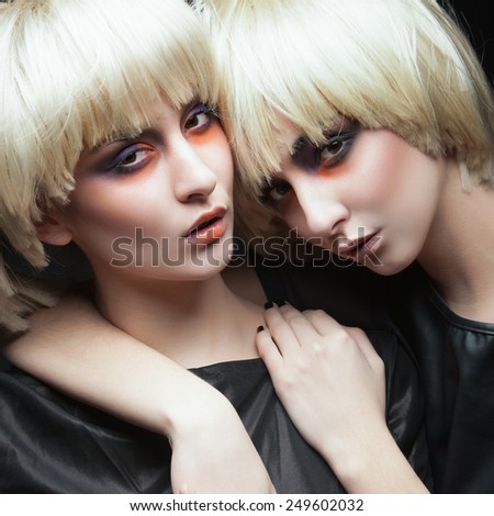 Portrait of two beautiful young girls twins blonde in the studio on a black background, the concept of beauty