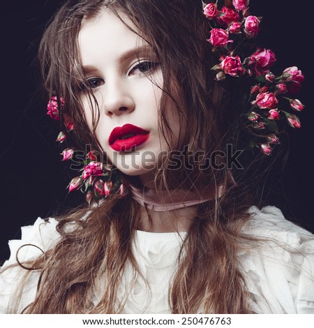 Portrait of beautiful girl in the studio on a black background with roses, concept of beauty and health