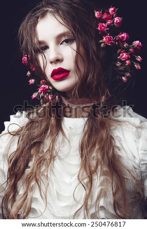 Portrait of beautiful young girl in the studio on a black background with roses, concept of beauty and health