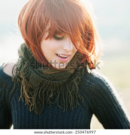 Portrait of a happy beautiful young girl with red hair in the field, lifestyle
