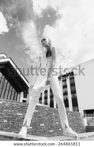 Black and white portrait of a beautiful young girl in a white clothes on the street in full growth