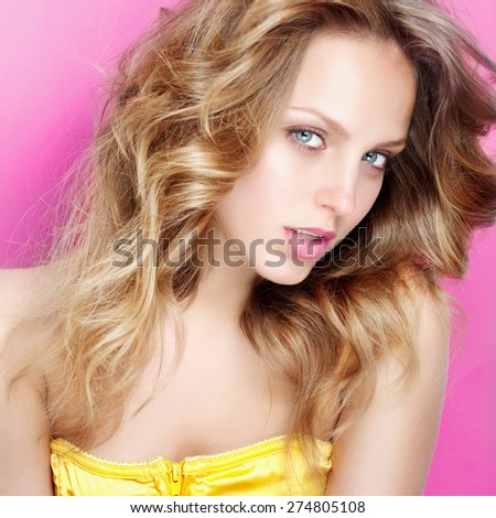 Portrait of a beautiful and gentle blonde girl in the studio on a pink background in a yellow dress, the concept of beauty
