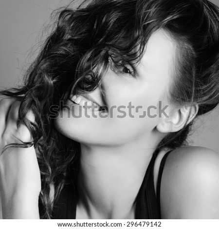Portrait of a beautiful laughing young brunette woman in a black shirt in the studio, in black and white photograph, close-up