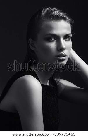 Black and white portrait of a beautiful girl in the studio on a black background