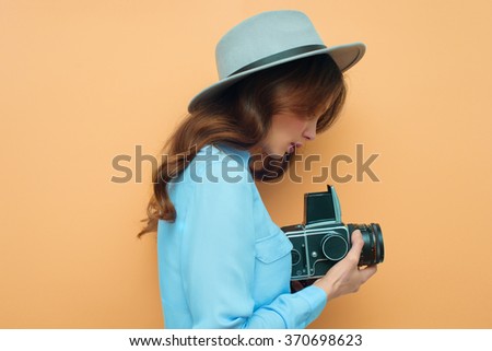 Young woman with camera. Brunette in a blue shirt. Hipster fashion photographer girl. Young people, youth culture