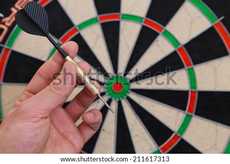 dart in a hand and a dartboard