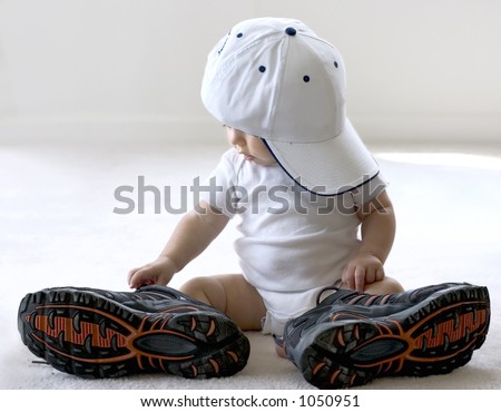 Adorable baby trying on shoes that are way too big for him