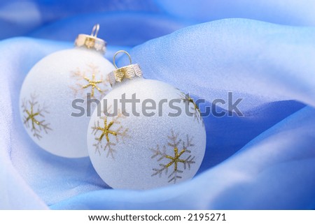 white christmas ornaments with golden snowflakes ob blue fabric