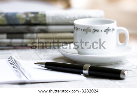 morning newspapers, cup of coffee and pen with notebook