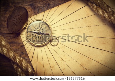 Old compass and rope on vintage paper. Adventure stories background. Retro stale.