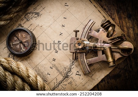 Old compass, astrolabe and rope on vintage map. Adventure stories background.