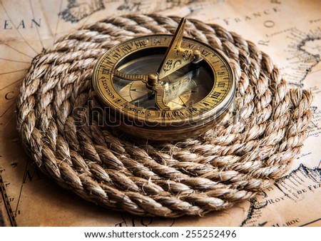 Old compass and rope on vintage map. Adventure stories background