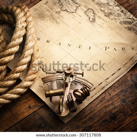 Astrolabe and rope on vintage map. Adventure stories background.