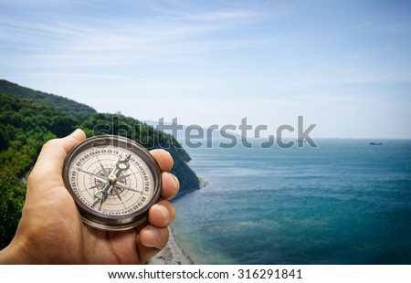 Compass in the hand on the nature background.