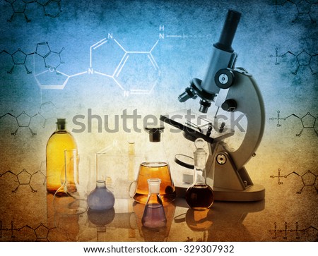 Test glass flask with solution and microscope in research laboratory. Science and medical background. Focus in the foreground.