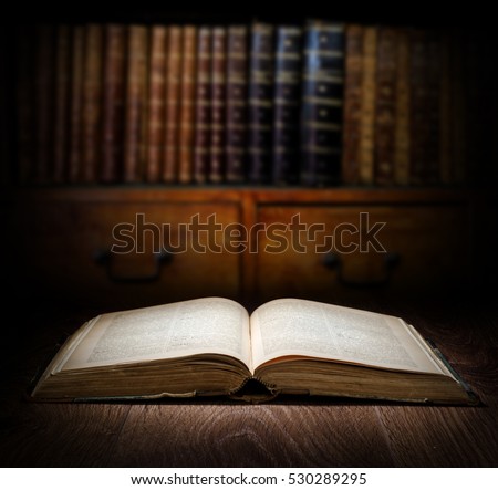 Open old book on a bookshelf background. Selective focus