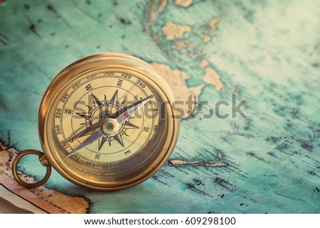 Old compass on vintage map. Adventure stories background. Retro style.