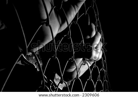 stock photo Handcuffed hands holding fence