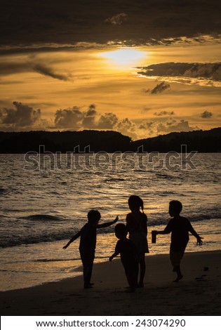 silhouette picture of children playing together on the beach in sunset