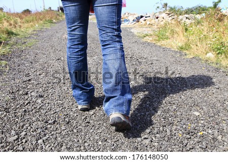 lady wear in jeans and walking shoes walking on countryside road in sunday under blue sky