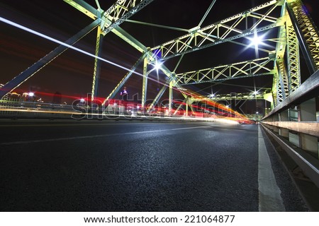 cars run fast across the highway of colorful steel bridge at night