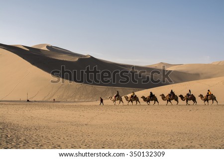 Dunhuang,Gansu, China - October 11, 2014: Group of tourists are riding camels in the desert at Dunhuang City , China. This place is a part of silk road in the history.