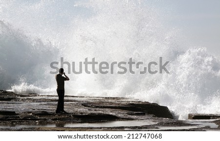 Person watching a huge powerful wave crashing against the rocks
