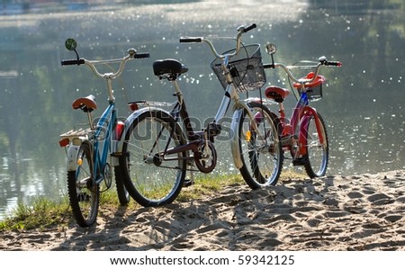 Three colorful bicycles parked against water on the beach, family travel.