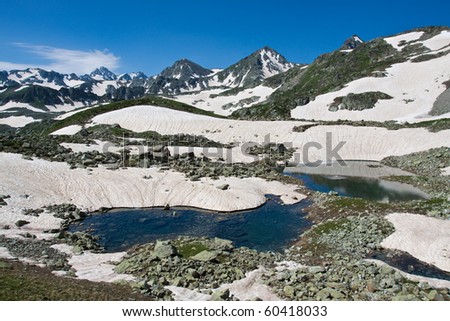 Mountain peaks landscape with crystal river, snow and sky.