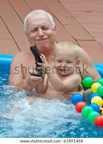 Grandfather and grandson relaxing in swimming pool, with colorful balls. Lifestyle family picture.