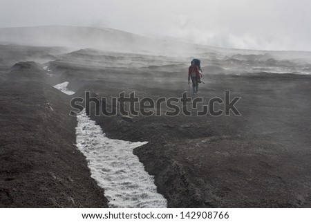 Hiker moving on volcano land in Kamchatka, Russia.