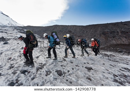 Hikers moving on volcano land in Kamchatka, Russia.