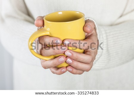 Cup of tea or coffee in female hands close up. Cold weather concept.